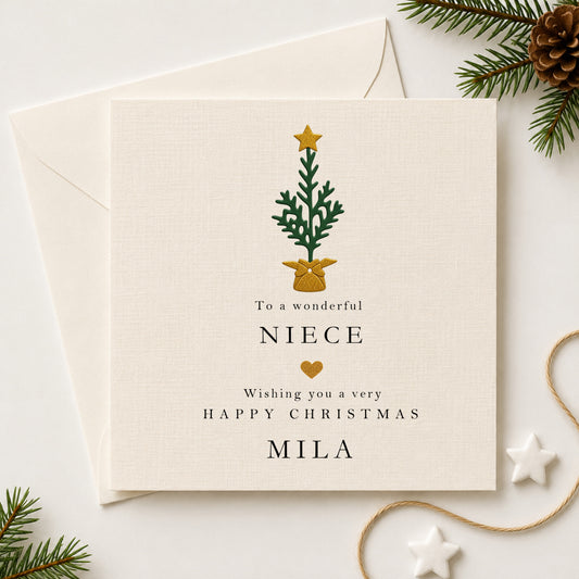 Personalised Christmas card for niece featuring a hand-layered green Christmas tree with gold star and gold bow pot, personalised with the name Mila, sent with a white envelope